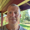 A middle-aged man with short gray hair looks at the camera outdoors.